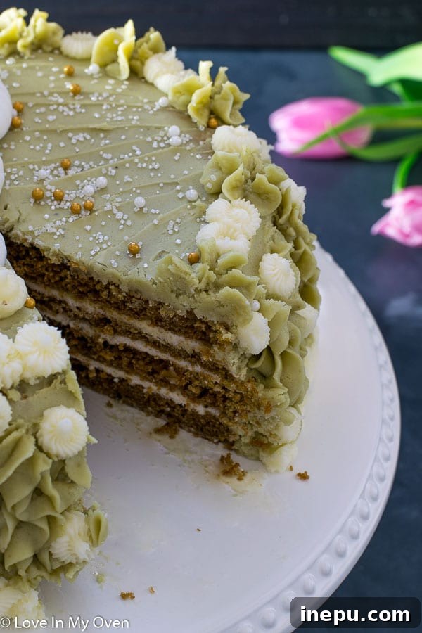 Matcha Vanilla Cake on a stand with a slice removed