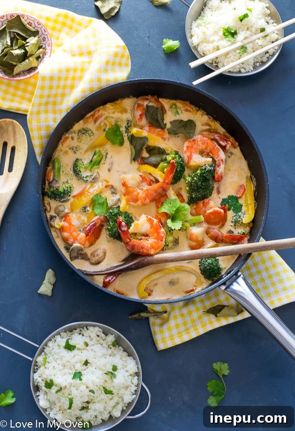 Delicious Red Thai Prawn Curry served with cauliflower rice, garnished with fresh cilantro and a lime wedge.