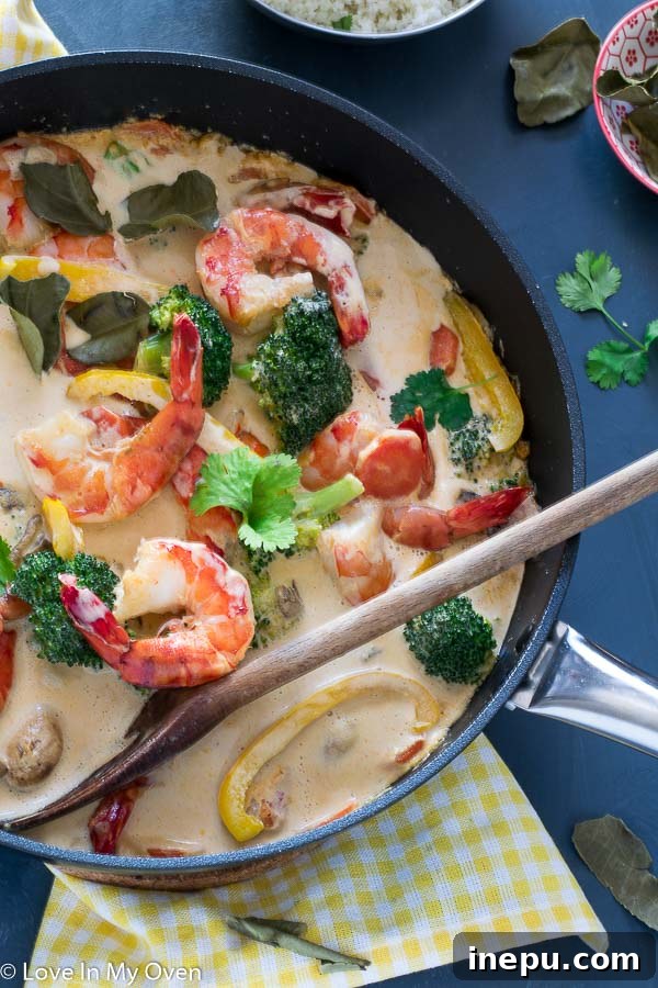 Close-up of a bowl of creamy Red Thai Prawn Curry with various vegetables and prawns, ready to be served.