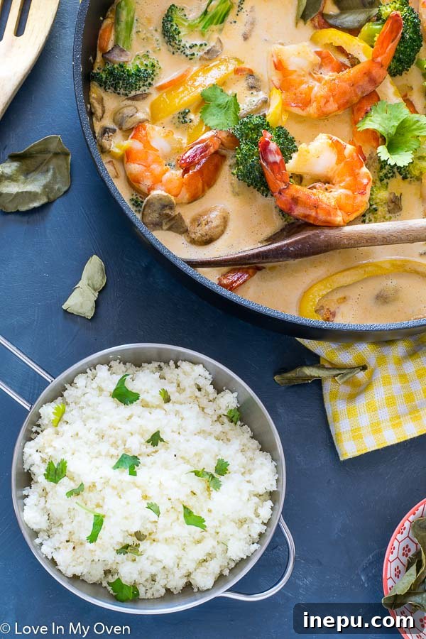 A beautifully plated dish of Red Thai Prawn Curry with cauliflower rice, ready to be enjoyed.