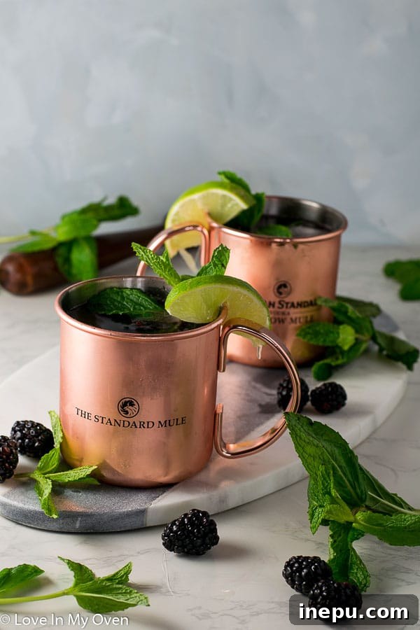 The Bramble Mule 3 Close-up of a Blackberry Mint Moscow Mule with ice, mint, and blackberries, showcasing its vibrant colors.