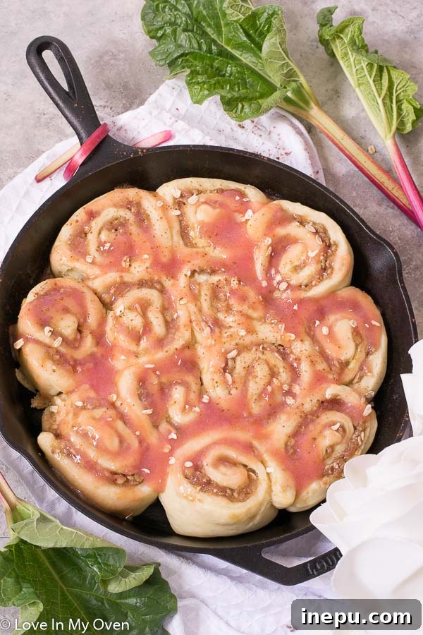Close-up of freshly baked Rhubarb Streusel Rolls, showcasing their golden-brown tops, gooey filling, and streusel texture, nestled in a baking pan.