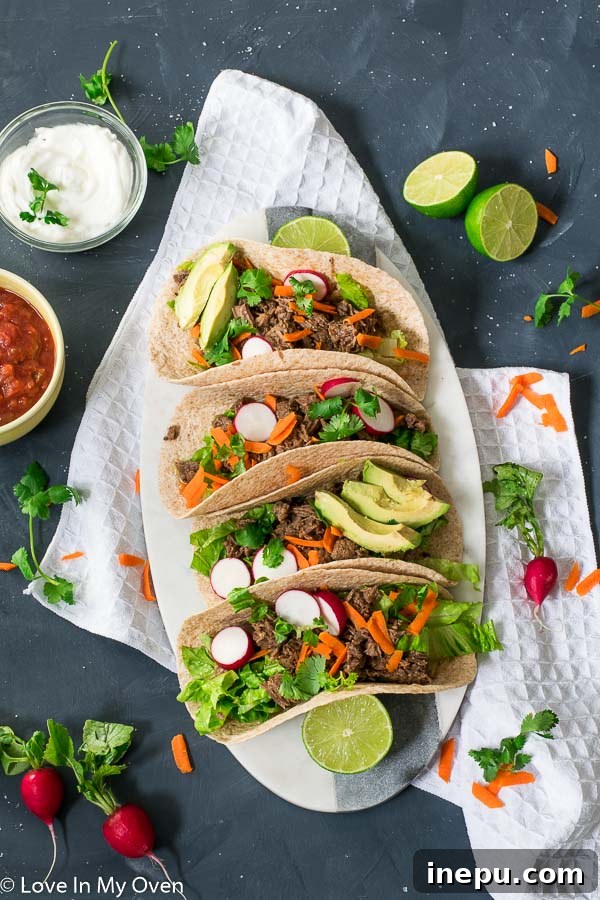 Hand holding a delicious Instant Pot Beef Barbacoa Taco with fresh toppings.
