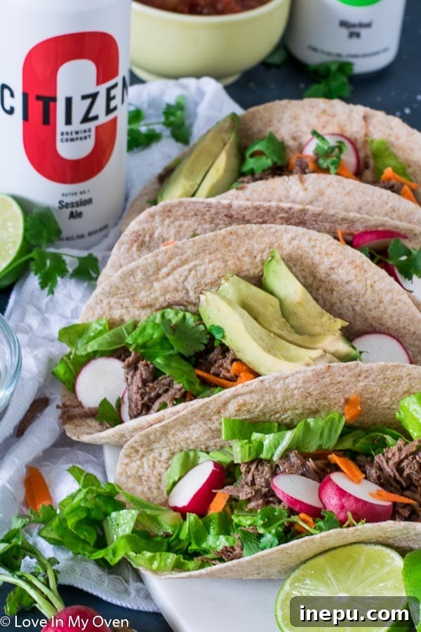 A plate of two Instant Pot Beef Barbacoa Tacos with various fresh toppings.