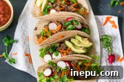 Close-up of Instant Pot Beef Barbacoa Tacos with fresh ingredients, ready to eat.