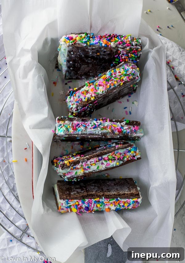 Two halves of a birthday cake ice cream sandwich, showcasing the vibrant sprinkle-filled ice cream and rich chocolate cookies.