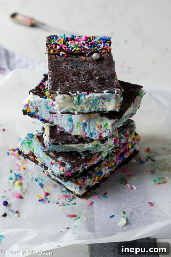 A stack of beautifully decorated birthday cake ice cream sandwiches, individually wrapped in parchment paper and ready for the freezer.
