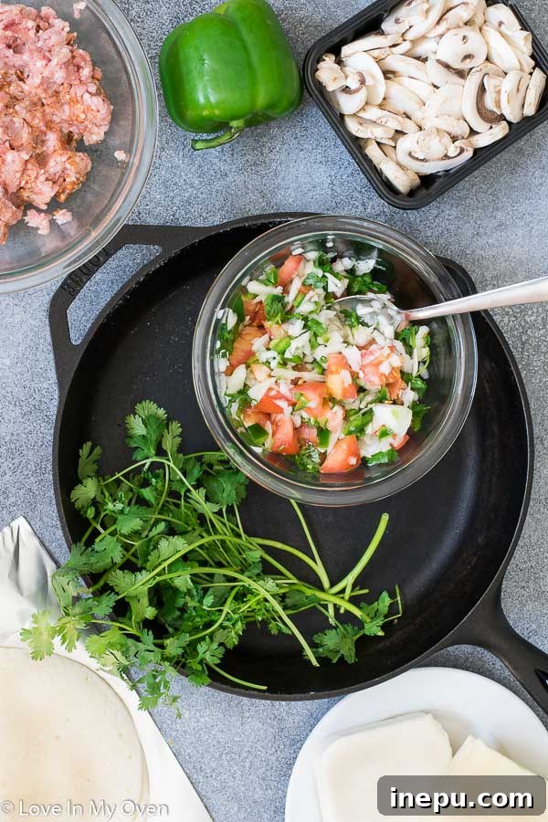 Raw ingredients for Queso Fundido including homemade chorizo, pico de gallo, and shredded cheese.