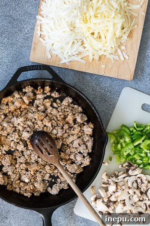 Sautéing diced peppers and mushrooms in a cast iron skillet on the grill.