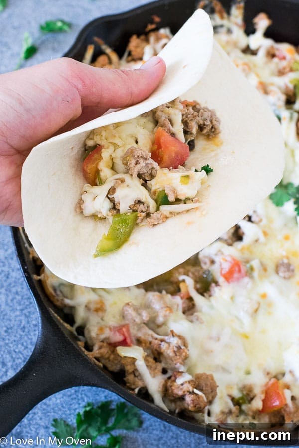 Serving Queso Fundido with chorizo in a cast iron skillet with warm tortillas.