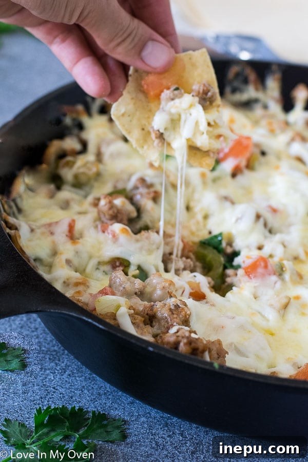 Scooping hot Queso Fundido with chorizo onto a warm flour tortilla.