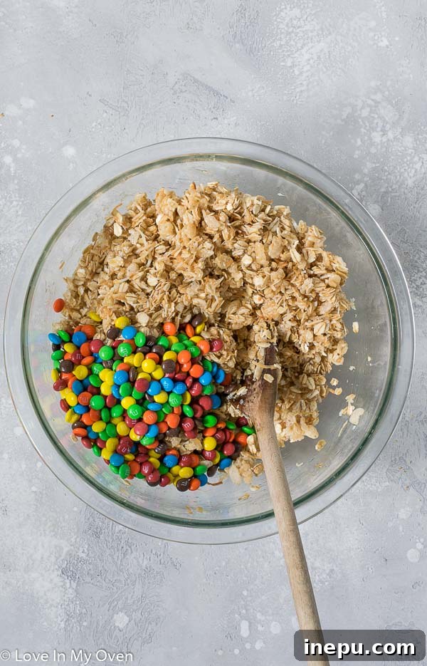 A baking dish filled with firmly pressed M&M granola bar mixture, chilling in the refrigerator.