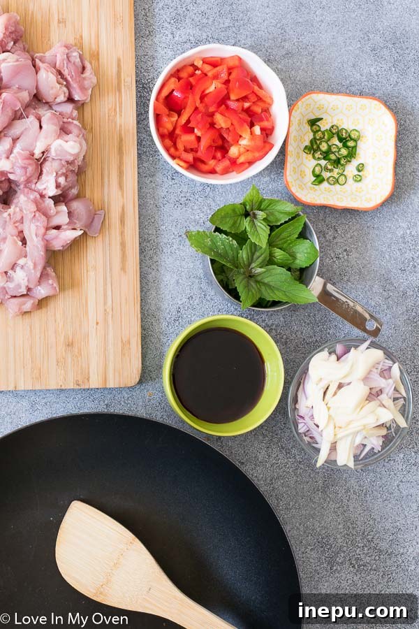 Diced chicken thighs and prepared vegetables ready for cooking Thai basil chicken.