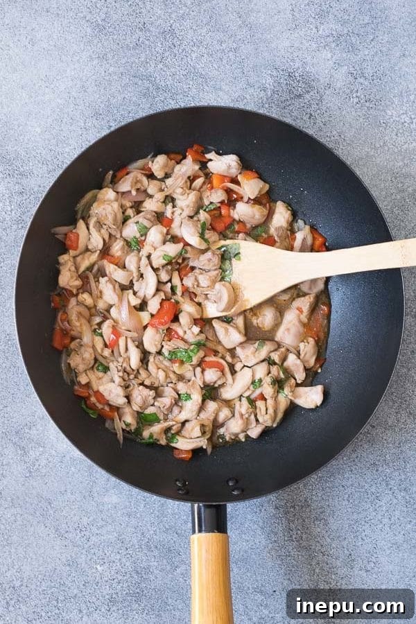 A mix of aromatic spices including sliced chilies, shallots, and garlic for Thai basil chicken.