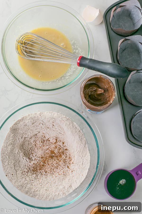 Unbaked Nutella muffin batter in a baking tin, ready for swirling and baking, showcasing the initial Nutella drop.