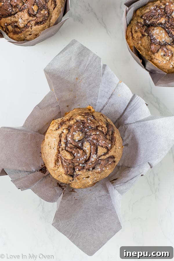 A stack of three golden-brown Nutella swirl muffins with sparkling sugar, highlighting their inviting texture.