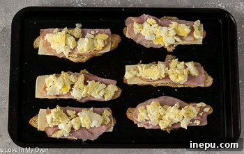 Placing scrambled eggs on croissant sandwiches