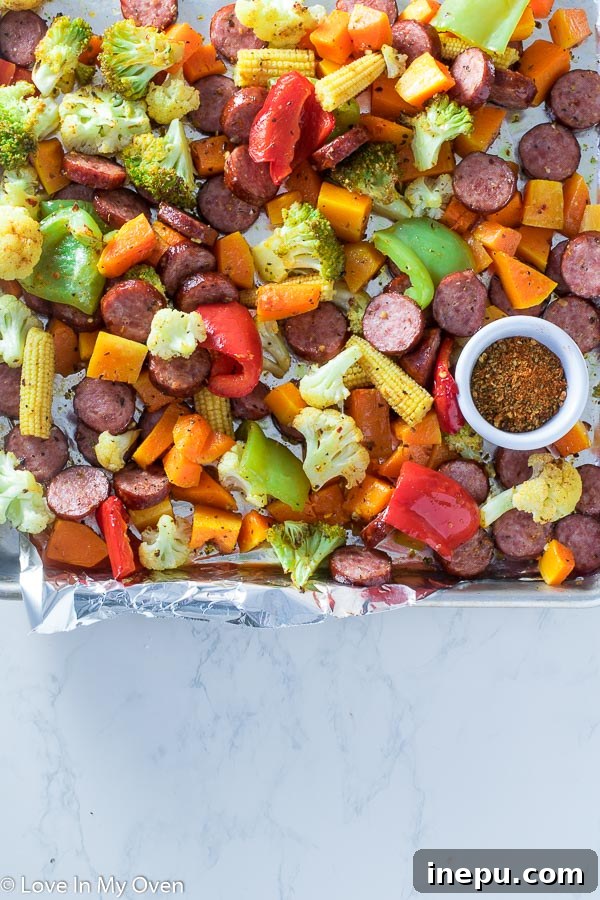 Overhead view of a cooked sheet pan sausage and roasted vegetables dinner, ready to be served.