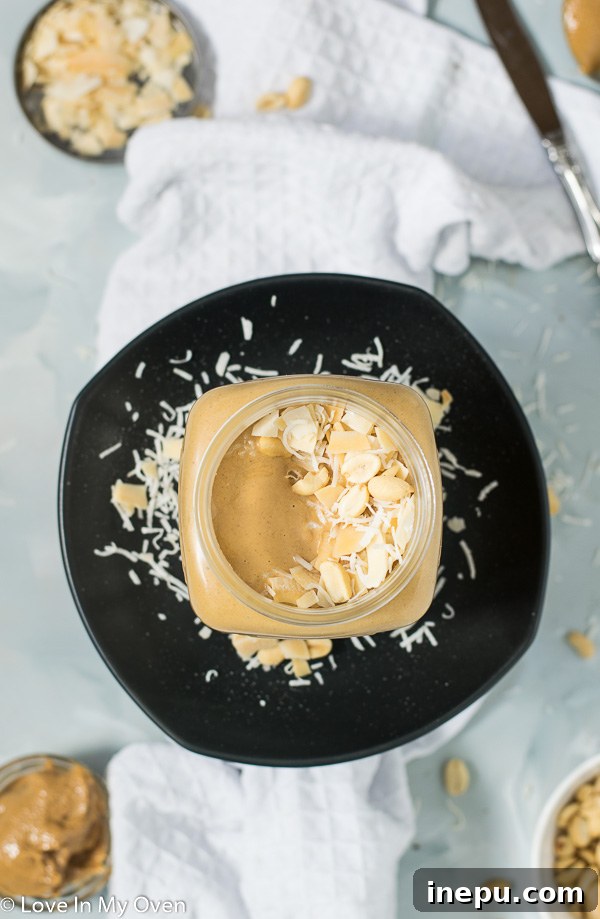 Tropical Nut Butter Bliss 6 A spoon dipping into a jar of fresh coconut peanut butter