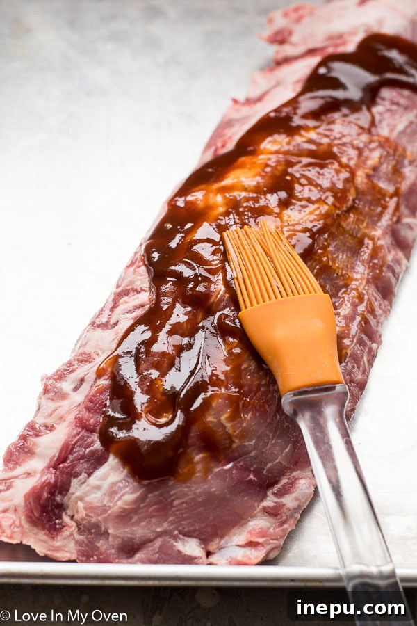 Melt-in-Your-Mouth Slow Cooker Ribs 4 Applying barbecue sauce to ribs for slow cooking