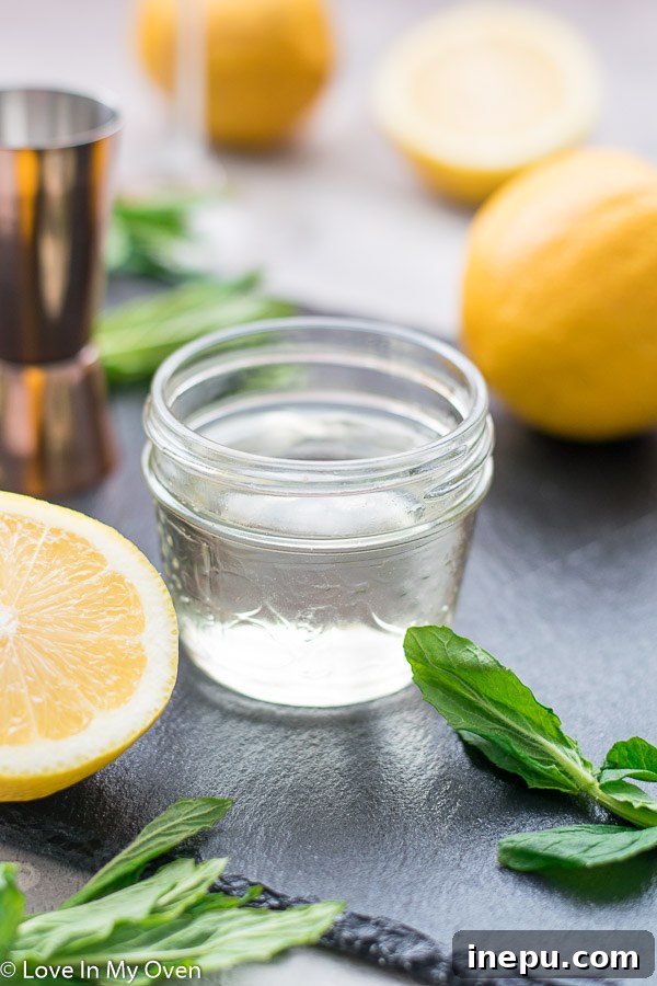 Ingredients for a lemon vodka cocktail, including fresh lemons and simple syrup.