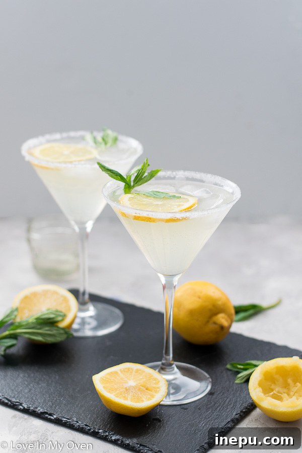Two glasses of lemon vodka cocktail on a wooden surface.