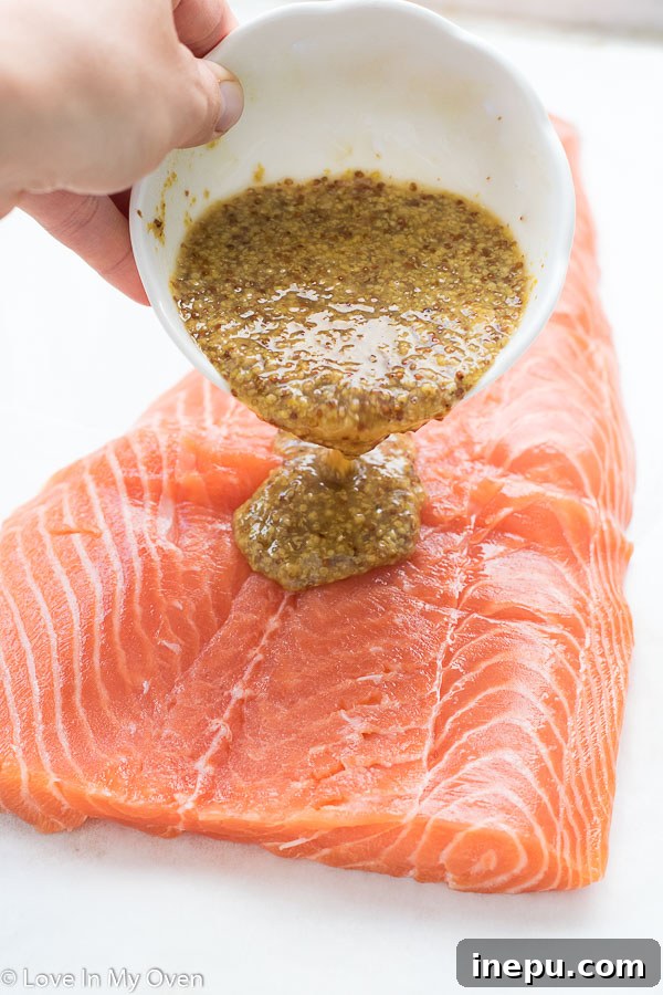 close-up of maple dijon glaze being applied to salmon