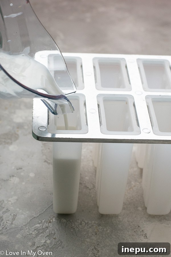 Zesty Coconut Lime Bliss 4 Partially frozen coconut lime popsicle mixture in molds, ready for sticks and topping.