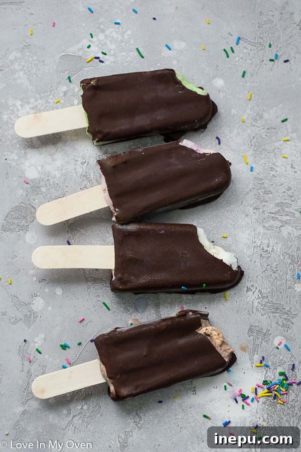 Finished chocolate dipped ice cream bars with a decorative white chocolate drizzle on a light background