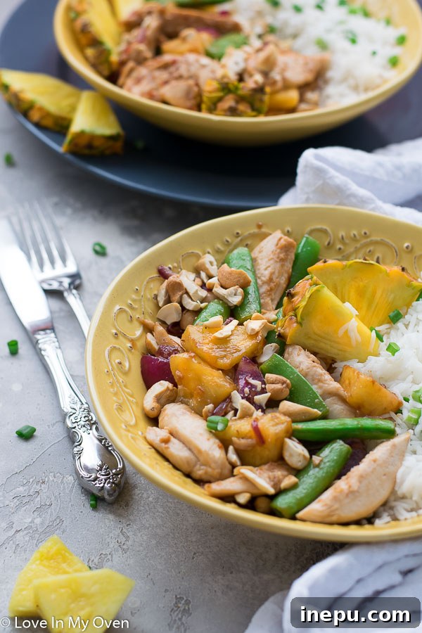 Golden Pineapple Chicken Stir-Fry 9 Scooping a portion of chicken and pineapple stir fry onto a plate, showing the rich sauce and tender ingredients.