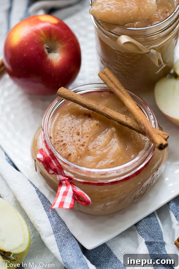 Kitchen Crafted Sugar-Free Applesauce 7 Several mason jars of homemade unsweetened applesauce, with a rustic kitchen towel and a few fresh apples, emphasizing the natural ingredients.