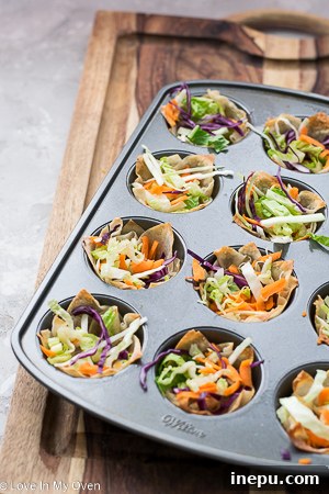 Close-up of shredded cabbage and carrot mixture being placed into baked wonton cups.