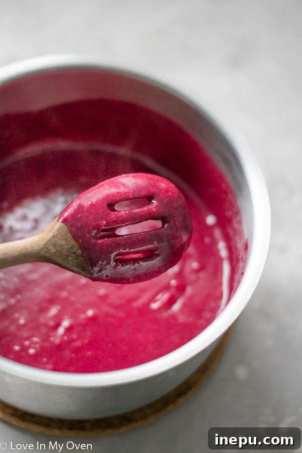 Thickening cranberry curd in a saucepan with egg yolks.