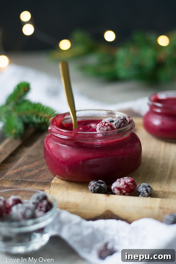 Close-up of cranberry curd in a jar with a spoon.