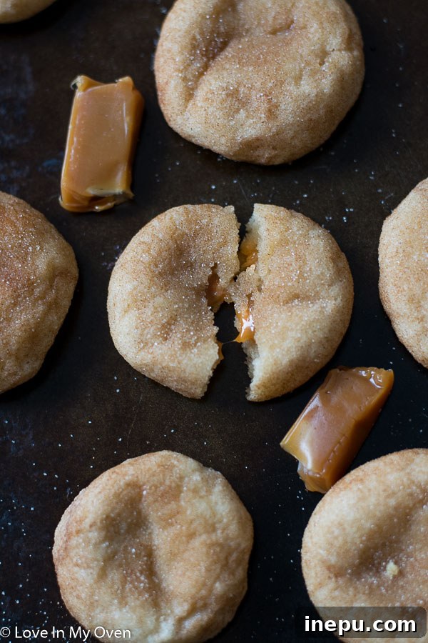 Decadent Caramel Snickerdoodles 9 Freshly baked caramel snickerdoodles cooling on a wire rack, with a few cut open to show the caramel