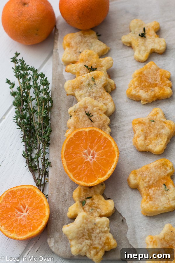 Golden Cheddar Thyme Shortbread 11 Several star-shaped thyme and cheddar cheese cookies artfully arranged on a serving plate with fresh thyme, ready for a party.