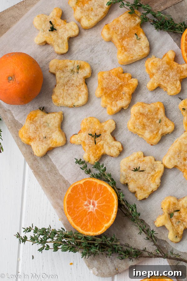 Golden Cheddar Thyme Shortbread 3 Multiple thyme and cheddar cheese cookies arranged neatly, showcasing their texture and golden color, with fresh thyme scattered around.