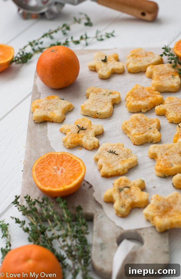 Golden Cheddar Thyme Shortbread 10 A large stack of golden brown thyme and cheddar cheese cookies, resting on a wire rack to cool, with fresh thyme scattered around.