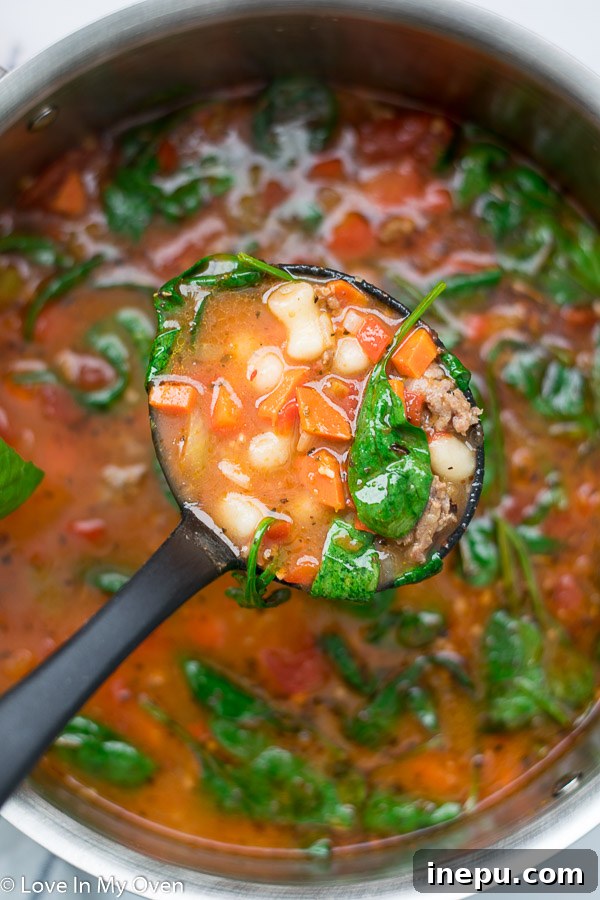 Sausage gnocchi soup in a bowl with fresh parmesan