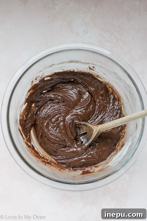 Effortless 3-Ingredient Nutella Brownies 5 Pouring the smooth Nutella brownie batter into a parchment-lined baking pan.