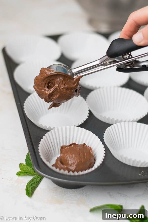 Minty Chocolate Dream Cupcakes 4 Cupcake batter being scooped into cupcake liners in a baking tray.