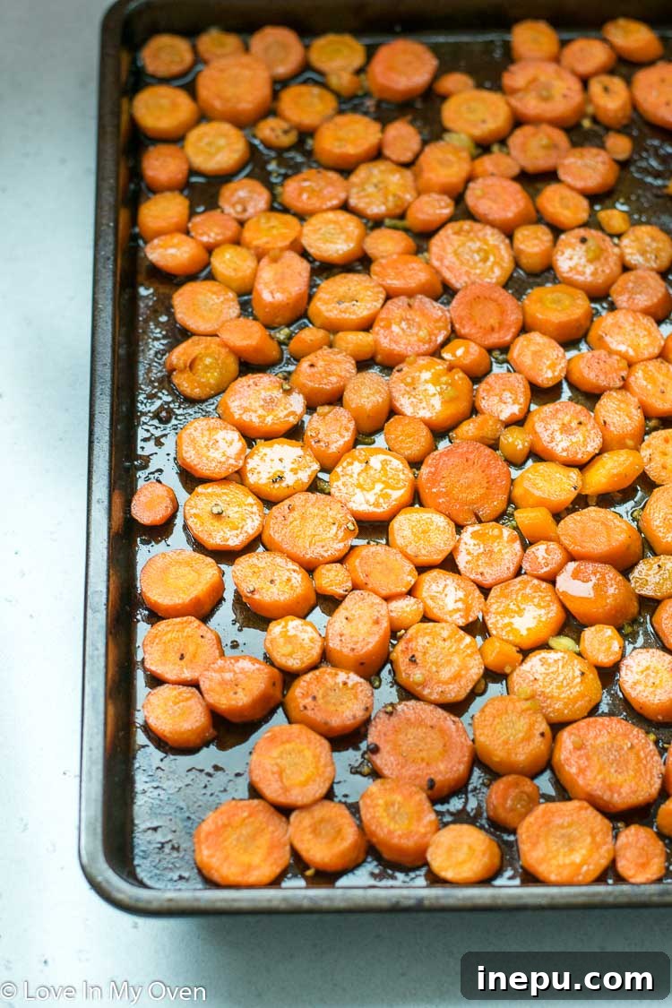 Garlic butter carrots spread on a baking sheet before roasting
