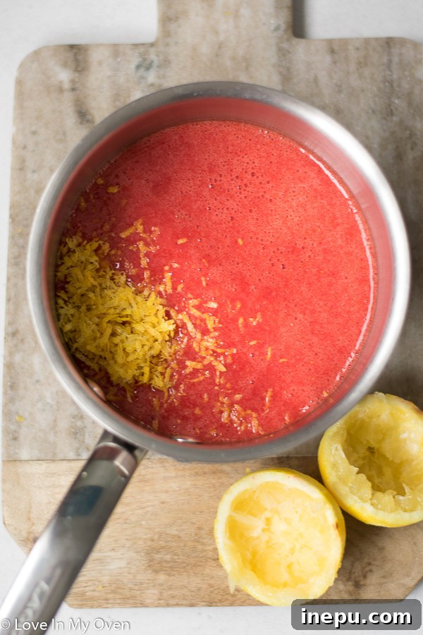 Luscious Strawberry Lemon Curd 5 Strawberry lemon curd thickening in a saucepan, being stirred with a whisk.