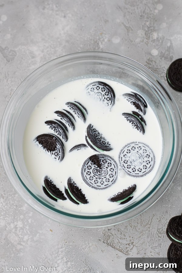 Mint Oreos soaking in heavy cream in a glass bowl