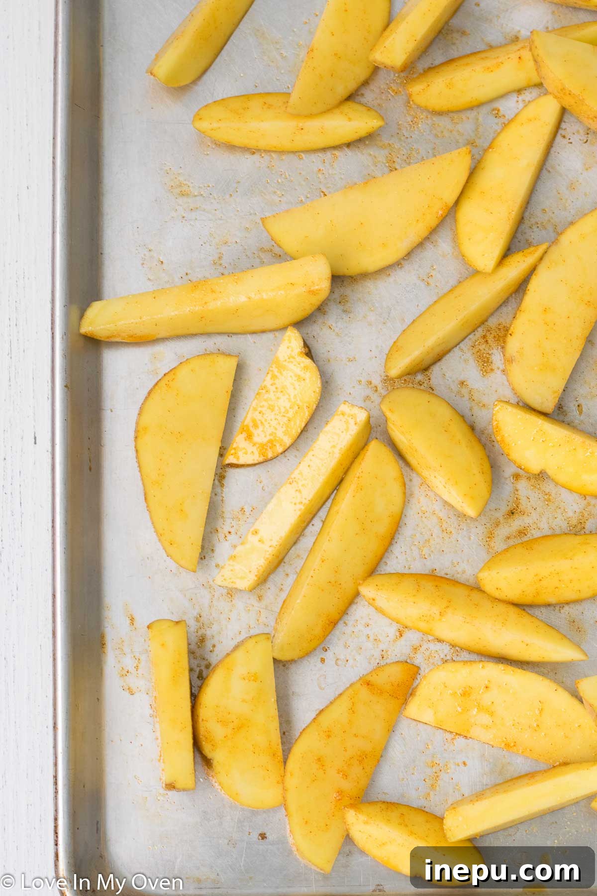 Seasoned potato wedges and High Liner fish fillets on a baking sheet