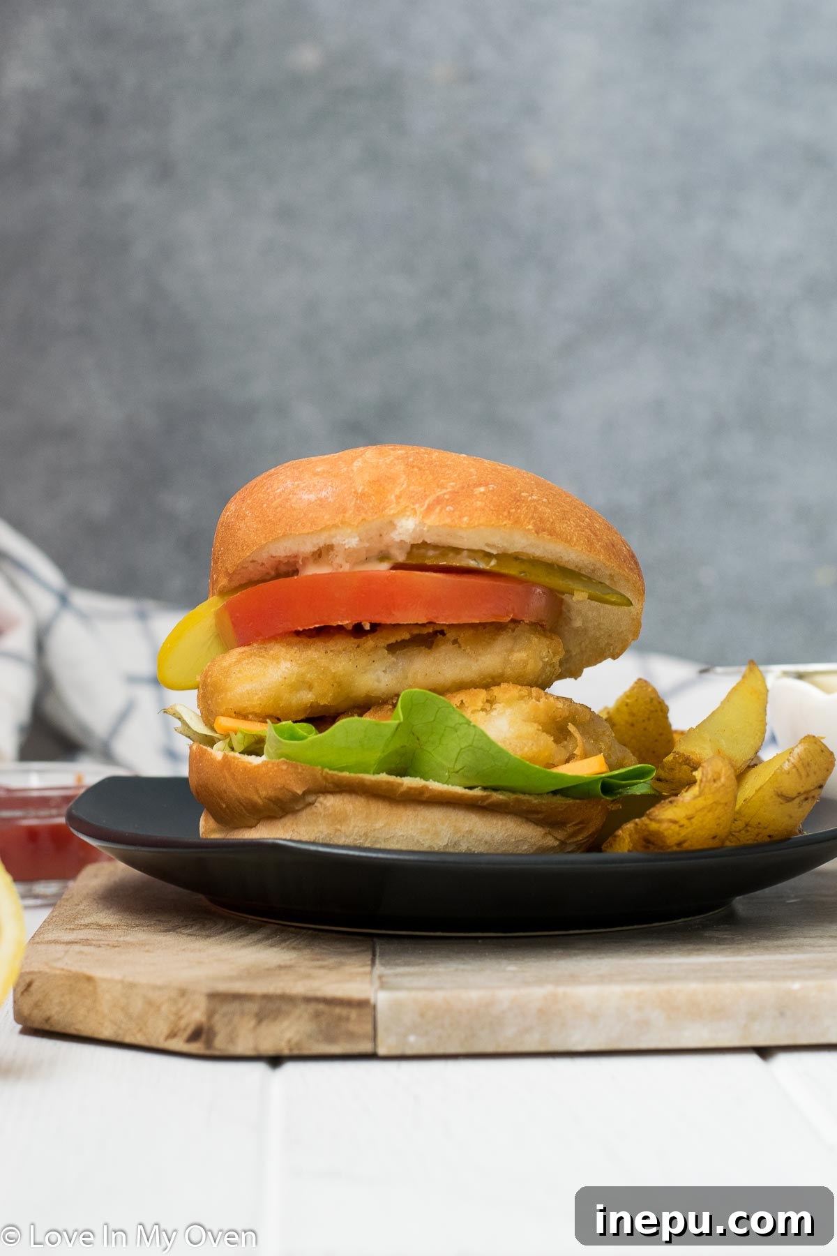 Two crispy fish burgers with potato wedges on a wooden board
