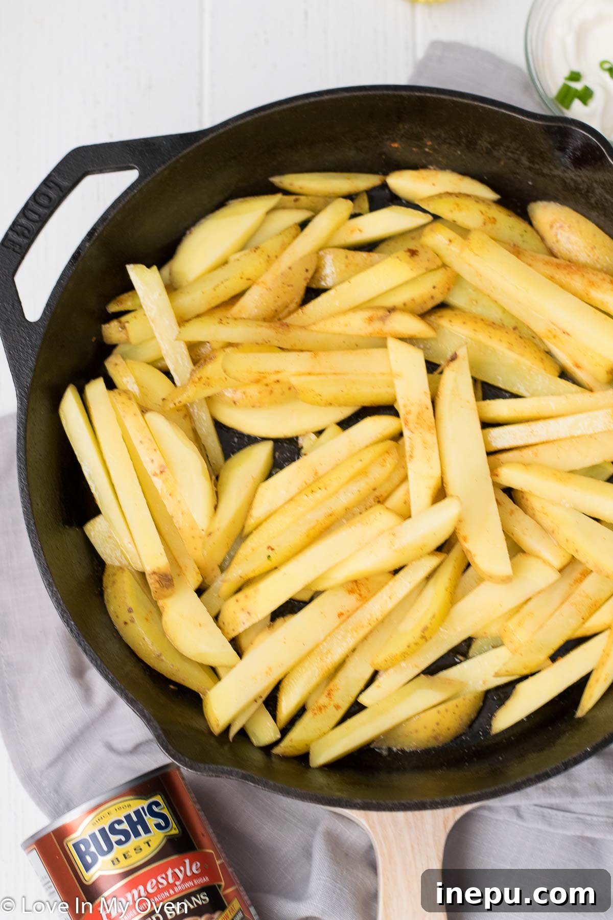 Sliced potatoes cooking in bacon grease in a cast iron skillet