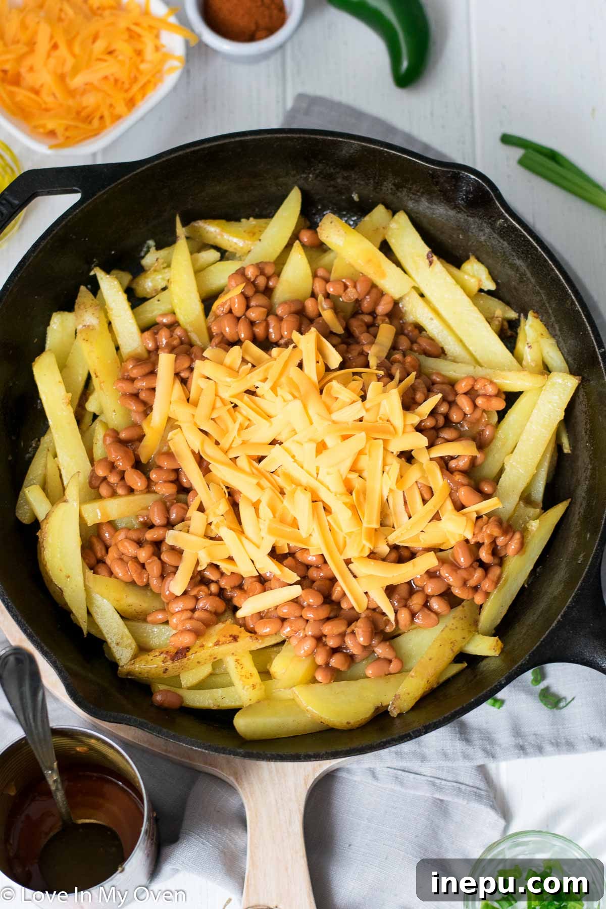 Skillet Loaded Cheese Fries baking in the oven, cheese melting