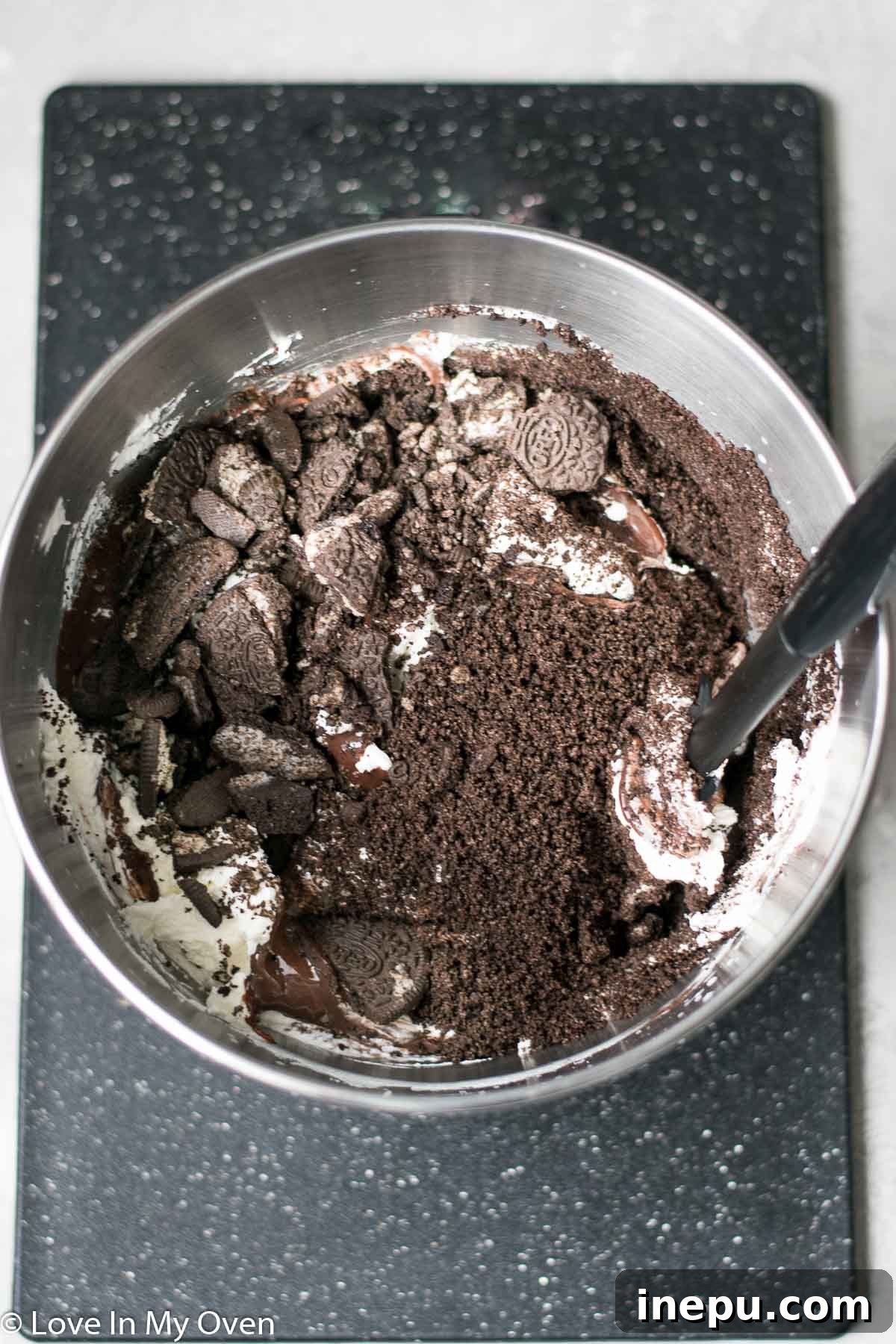 Decadent No-Churn Chocolate Oreo Delight 7 Folding crushed Oreos and chocolate condensed milk into whipped cream.