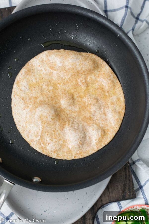 No-Fuss Huevos Rancheros 5 Spreading refried beans on a warm tortilla for huevos rancheros